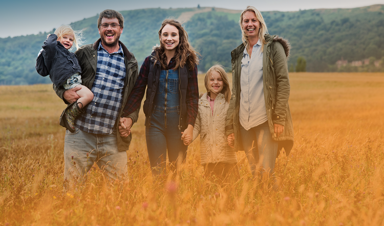 Vijf gelukkige familie-leden in veld.